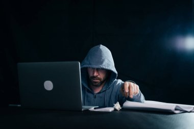 bir dizüstü bilgisayarda yasadışı bir şey yapıyor yüzünü, gizemli bir suç erkek hacker gizler