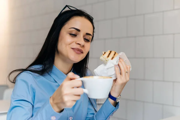 カフェでランチのサンドイッチとコーヒーを持っている青いシャツを着てかわいい笑顔の女の子 — ストック写真