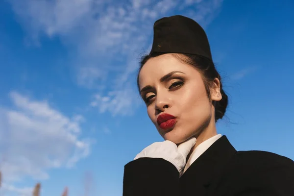 Mignonne hôtesse attrayante fille en uniforme se tient sous le ciel bleu — Photo