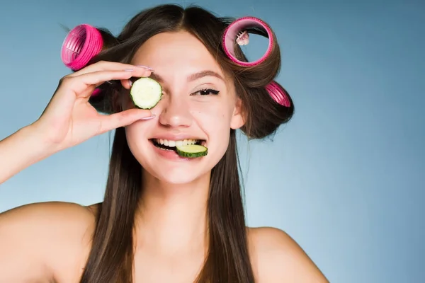 Garip bir genç kız iyi, curlers, Cilt nemlendirici için tutan bir salatalık başkanı bakmak istiyor — Stok fotoğraf