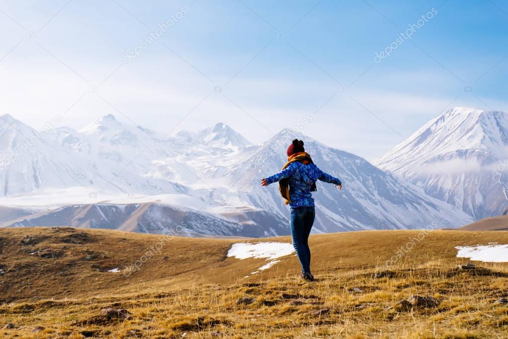 active young girl in a blue jacket enjoying the mountain nature and air