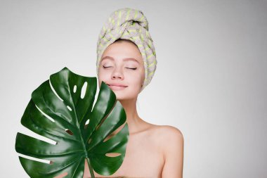 Kafasındaki bir havlu ile genç kız büyük bir yaprak tutar