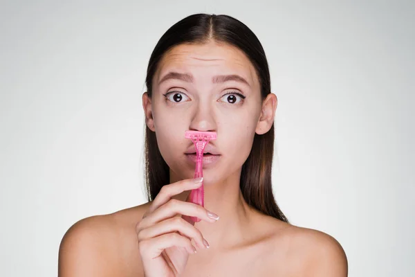 Young girl holding a razor on a gray background — Stock Photo, Image