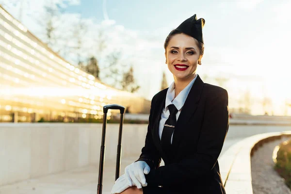 Счастливая стюардесса девушка с чемоданом на голубом фоне неба — стоковое фото