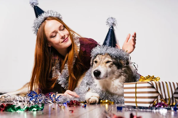 穿着新年套装的女孩坐在狗和新年礼物旁边 — 图库照片