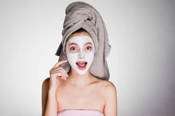 Une jeune fille avec une serviette sur la tête a appliqué un masque pour nettoyer la peau de son visage — Photo