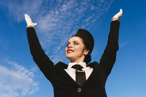 Letuška šťastná mladá žena v uniformě má rád létání, pod modrou oblohou — Stock fotografie