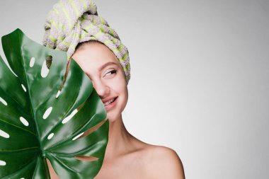 holding bir yaprak yeşil, gün spa başında bir havlu ile sevimli gülümseyen kız
