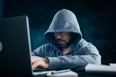 bir kazak bir kukuleta ile sakallı bir adam hacker bir dizüstü oturur