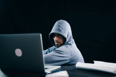 Bir hacker'bir kazak bir kukuleta ile bir laptop monitör görünüyor