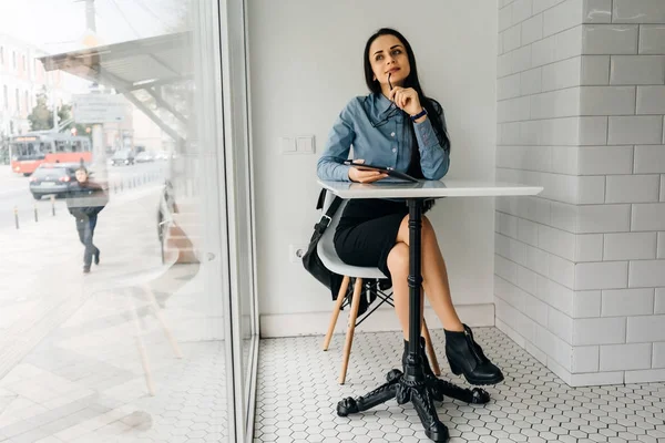 genç kız mavi gömlekli bir tablet tutan bir kafede oturuyor