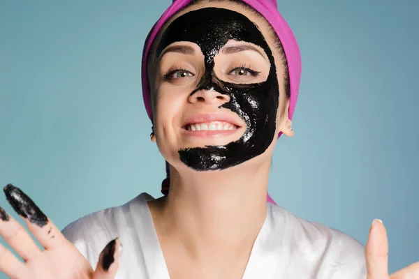 若い幸せな女の子が彼女の顔にマスクをクレンジング ブラックを適用します。 — ストック写真