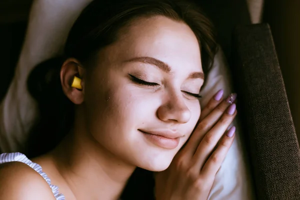 Młoda dziewczyna z zatyczkami do uszu w jej uszach śpi — Zdjęcie stockowe