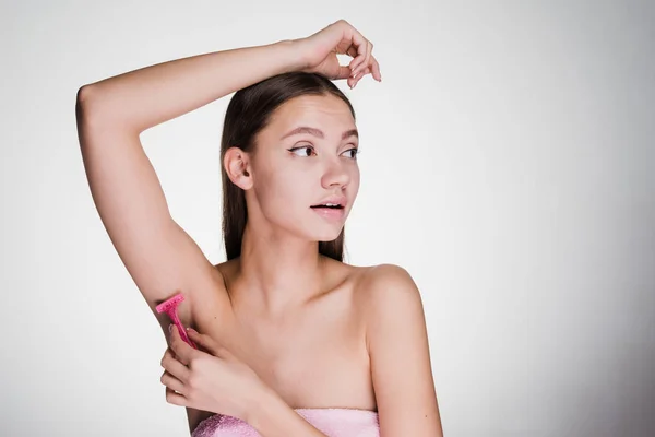 Linda joven se afeita el pelo en su axila con una navaja de afeitar — Foto de Stock