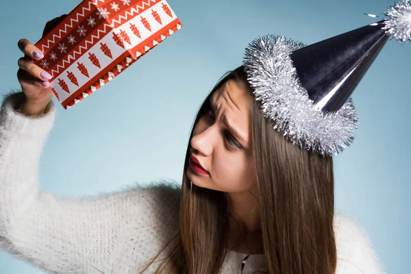 Een jong meisje in een New Year's hoed is ongelukkig met haar cadeau — Stockfoto