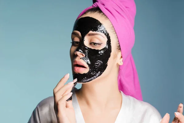 Ung flicka med rosa handduk på huvudet sätter på en svart mask — Stockfoto