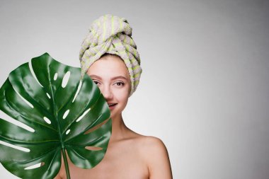 holding bir yaprak yeşil, gün spa başında bir havlu ile sevimli gülümseyen kız