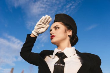 gökyüzüne, güneşin gözlerinden kapsayan bir genç hostes kız baktı