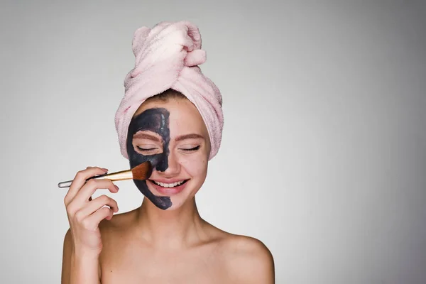 Молода дівчина з рушником на голові наноситься на маску для обличчя — стокове фото