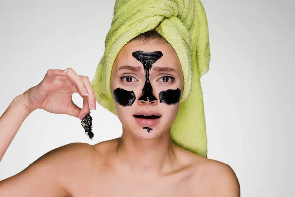 A frustrated girl with a towel on her head takes off the cleansing mask — Stock Photo, Image