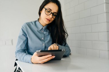 Genç kız masada oturan tablet bakarak