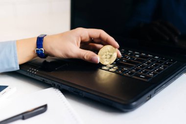 bir kız bir bitcoin tutan bir laptop oturuyor