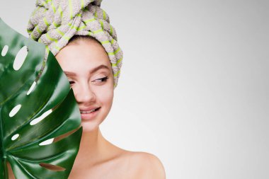 Kafasındaki bir havlu ile genç kız büyük bir yaprak tutar