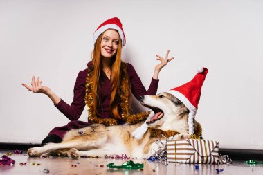 Genç kız bir Noel şapka onun köpek ile yere oturur