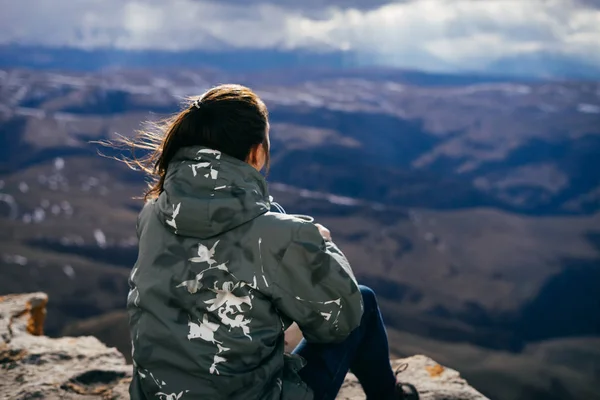 Chica turista es alta en las montañas en el borde del acantilado —  Fotos de Stock