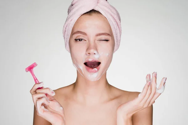 Girl with a towel on her head shaves her face — Stock Photo, Image