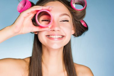 mavi zemin üzerine genç kız gülümseyerek curlers görünüyor