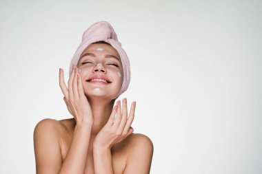 beyaz bir arka plan üzerinde eğleniyor başında bir havlu ile genç kız