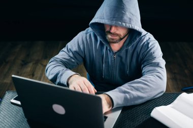 yakından ekrana bakarak bir dizüstü bilgisayar arkasında çalışan deneyimli bir hacker