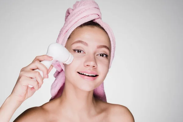 Giovane ragazza sorridente pulisce il viso su uno sfondo bianco — Foto Stock
