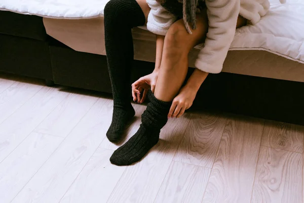 Girl in a dressing gown puts on warm leggings — Stock Photo, Image