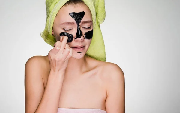 A young girl puts on her face a black mask — Stock Photo, Image