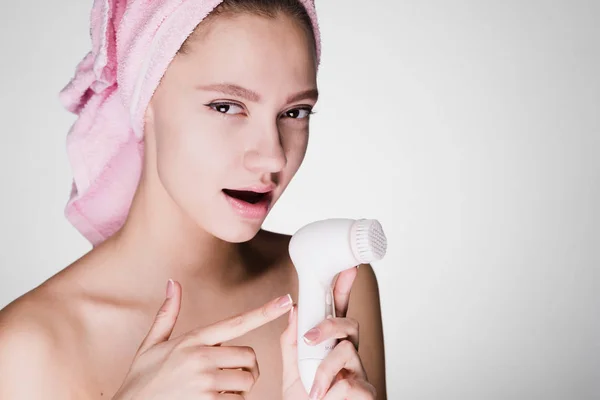 Giovane ragazza su uno sfondo bianco tiene un detergente per la pelle — Foto Stock