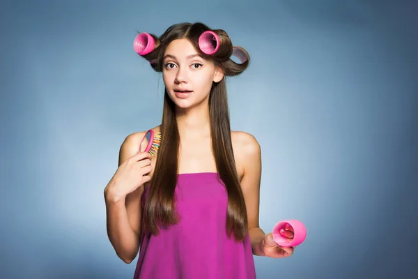 Girl with big curlers on her hair combs her hair — Stock Photo, Image