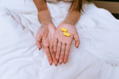 Kız sarı kulak tıkacı yatak arka plan üzerinde tutar.