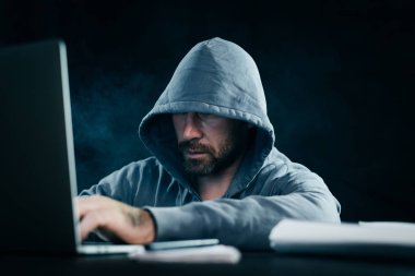 genç adam hacker bir kukuleta ile bir kazak'ı bir dizüstü oturur