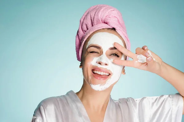Счастливая девушка с полотенцем на голове нанесите очищающую маску на лицо — стоковое фото