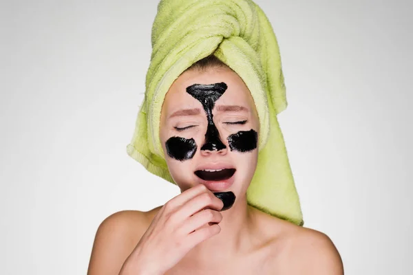 Girl with a towel on her head put a mask on problem areas and yawns — Stock Photo, Image