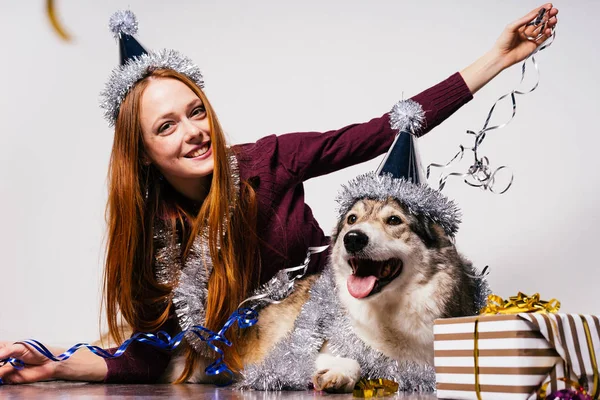年轻女孩微笑着戴着圣诞帽和她的狗坐在一起 — 图库照片