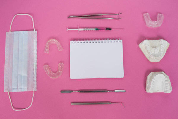 много зубных протезов на розовом столе
