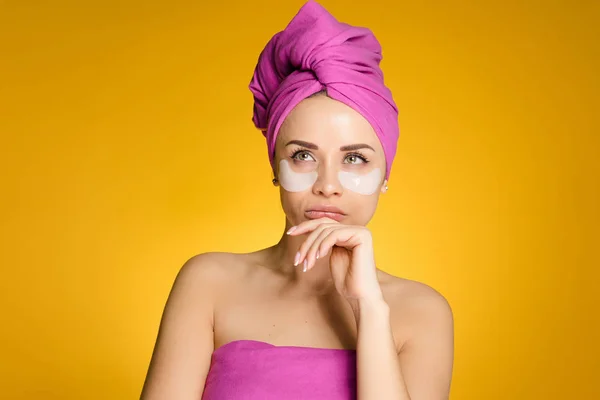 Flicka med en handduk på huvudet tillämpas en hydrogel mask under ögonen — Stockfoto