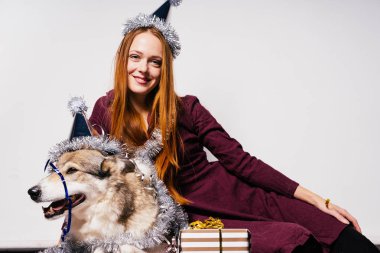 bir yılbaşı şapkalı bir kız büyük bir köpek ve hediyeler yanında oturur