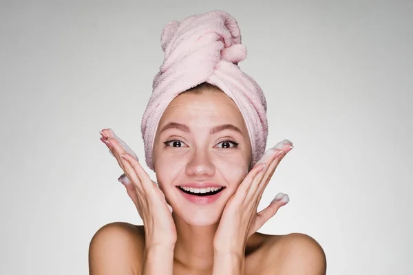 Jeune fille avec une serviette sur la tête souriant sur un fond blanc — Photo