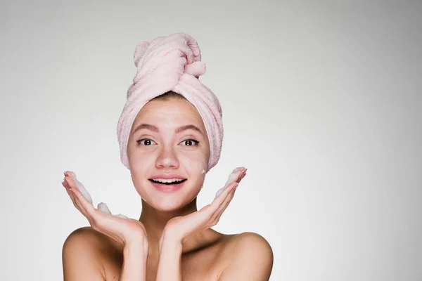 Счастливая девушка с полотенцем на голове на сером фоне — стоковое фото