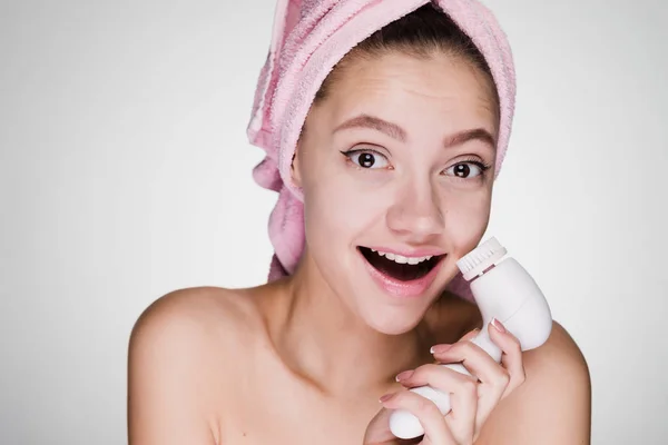 Happy girl with a towel on her head holds an electric brush in hands — Stock Photo, Image