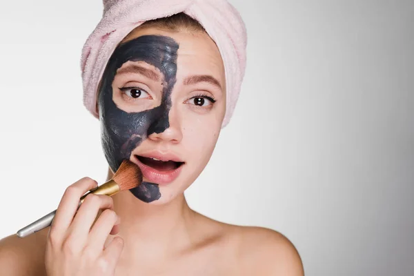 Flicka med en handduk på huvudet sätter på läpparna en svart mask — Stockfoto